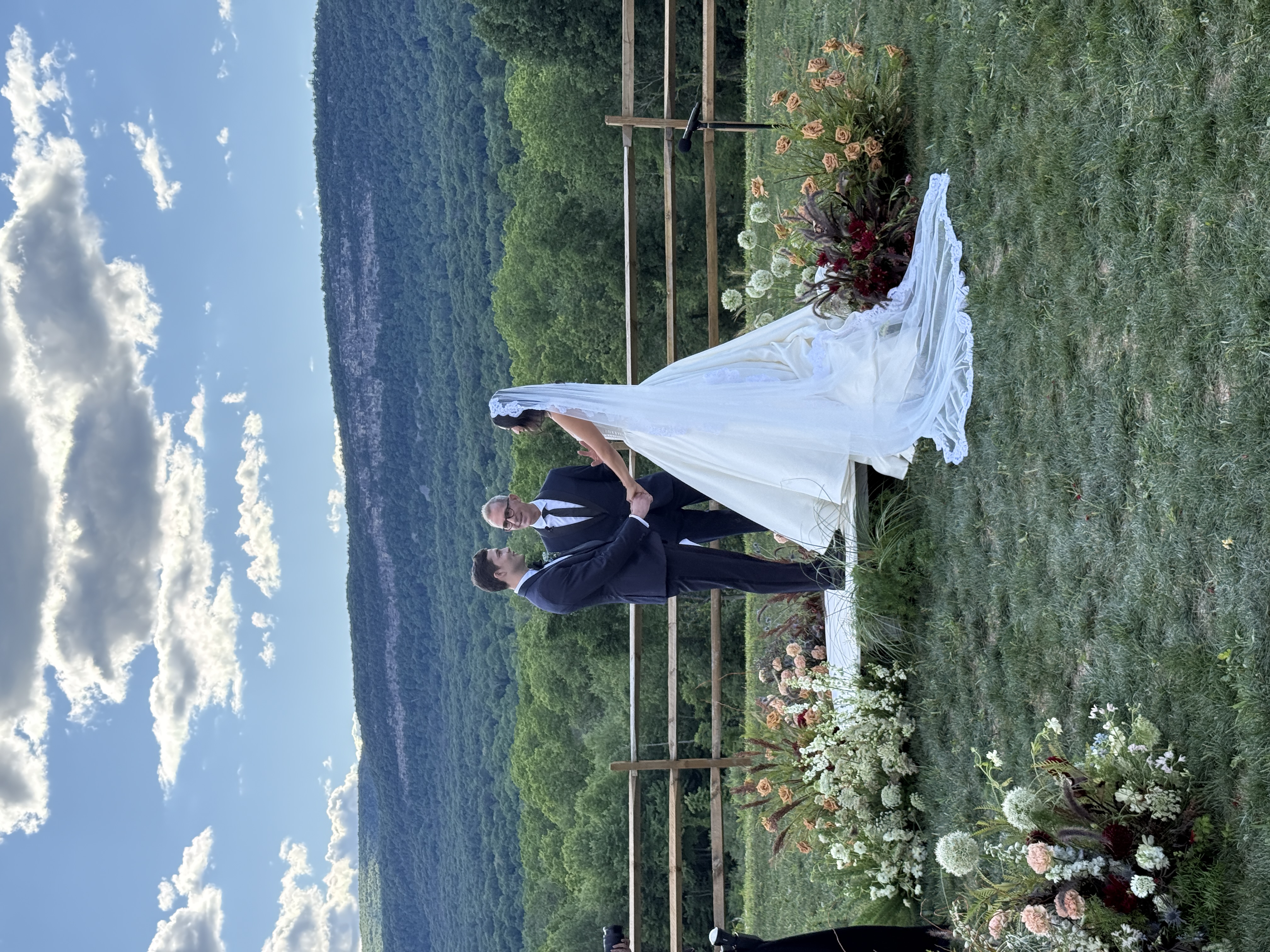 Bride and groom exchanging vows during an outdoor wedding ceremony with mountain views